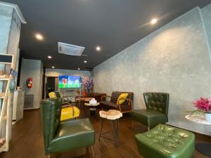 a living room with green chairs and a table at Bud Brew Beyond Dispensary and Hotel in Bangkok