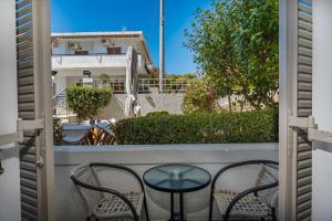 a patio with two chairs and a glass table at Erato Hotel in Agia Marina Aegina