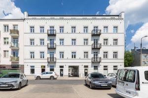 a white building with cars parked in front of it at Mińska Apartament in Warsaw