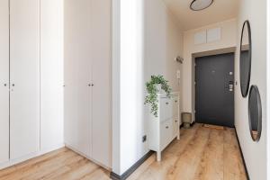a hallway with white walls and a black door at Mińska Apartament in Warsaw