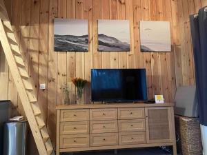 a television on a dresser with pictures on the wall at Casa Leo in Gujan-Mestras