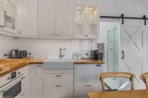 a kitchen with white cabinets and a sink at Warm, Inviting & Luxurious The Barn in Sandy Bay +4 photos
