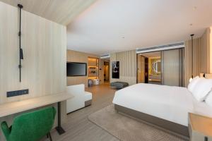 um quarto com uma cama, uma secretária e uma televisão em EVEN Hotel Qingdao Laoshan - an IHG Hotel em Qingdao