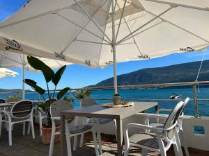 a table and chairs with an umbrella and the water at Apartments Sun House in Herceg-Novi