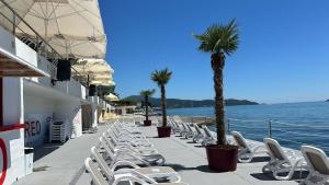 a row of chairs and palm trees next to the water at Apartments Sun House in Herceg-Novi +49 photos