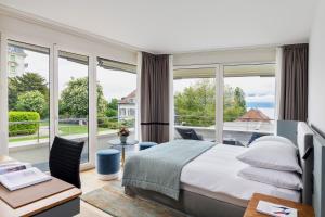 Un dormitorio con una cama y un balcón con ventanas. en Hotel Angleterre, en Lausana