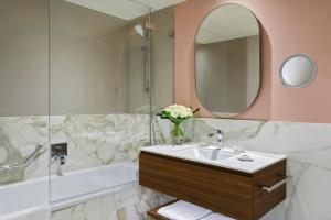 Un baño con lavabo, espejo y bañera. en Hotel Angleterre, en Lausana