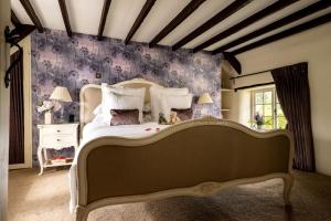 - une chambre avec un grand lit et du papier peint violet dans l'établissement Rose Cottage, à High Bickington