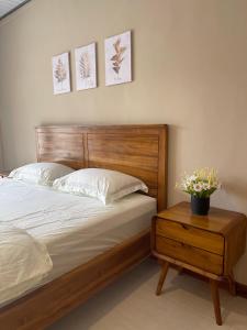 a bed with a wooden headboard and a table with a potted plant at Lestarindo Dvillas in Boyolali