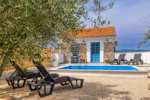a villa with a swimming pool and two chairs at Holiday house KUNTENTA with pool and jacuzzi in Skrbčići