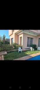 zwei weiße Bänke vor einem Haus in der Unterkunft H Amelkis in Marrakesch