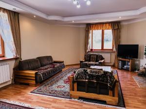 a living room with a couch and a tv at Kolsay Tanbalytas Villa in Kolʼbastau