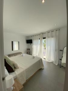 a white bedroom with a large bed and a window at Elegancia y confort en Casa Moncerrat in Vilanova i la Geltrú