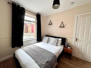 ein Schlafzimmer mit einem Bett mit weißen Laken und einem Fenster in der Unterkunft Central 4 Bedroom House With Driveway in Newcastle upon Tyne