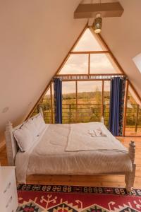 un lit dans une chambre avec une grande fenêtre dans l'établissement The Besotted Cottage at Mount Kenya Farm Stay, à Naro Moru