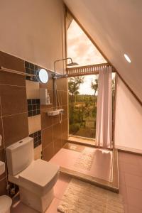une salle de bain avec toilettes et fenêtre dans l'établissement The Besotted Cottage at Mount Kenya Farm Stay, à Naro Moru