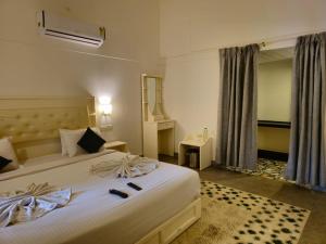 a bedroom with a large white bed with shoes on it at Olive Periyar in Thekkady
