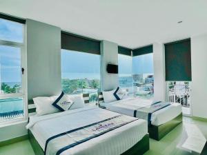 a bedroom with two beds and a large window at Lavender Muine Hotel in Mui Ne