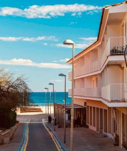a building on a street next to the ocean at La Perla de Sa Riera in Begur