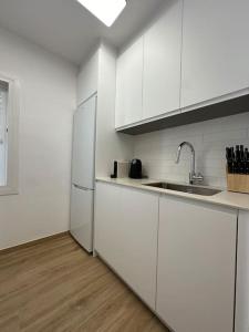 a white kitchen with a sink and a refrigerator at La Perla de Sa Riera in Begur +15 photos