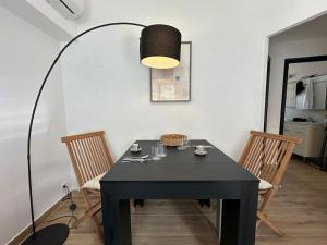 a black dining room table with chairs and a lamp at La Perla de Sa Riera in Begur