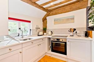 a kitchen with white cabinets and a sink at Abbey Nest in Battle