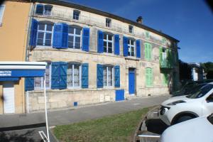 un bâtiment avec des volets bleus et verts dans une rue dans l'établissement Appartement Les Berges de l'Ornain, à Bar-le-Duc