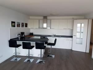 a kitchen with white cabinets and black counter tops at Neubau-Ferienwohnung mit Panorama-Seeblick in Bosau