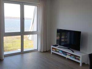 a living room with a flat screen tv and two large windows at Neubau-Ferienwohnung mit Panorama-Seeblick in Bosau