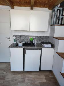 Una cocina con gabinetes blancos y un fregadero. en Loft duplex industrial near the sea bicicles, en Valencia