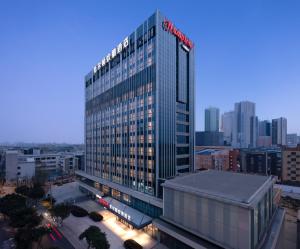 wysoki budynek z napisem na szczycie w obiekcie Hilton by Hampton Chengdu North Railway Station w mieście Chengdu