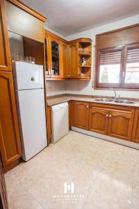 a kitchen with a white refrigerator and wooden cabinets at Casa en Rustical in Bonmont Terres Noves +61 photos