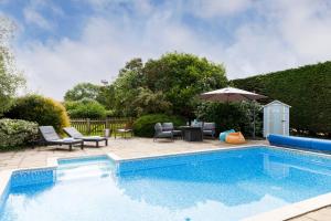 a swimming pool with a table and chairs and an umbrella at The Annex, Truffles, West Wittering in West Wittering