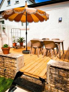 una terrazza in legno con tavolo e ombrellone di Hacienda Flats - Wunderschöne Ferienwohnungen am Seewald a Friedrichshafen