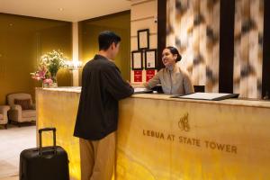 a man and a woman standing at a reception desk at Tower Club at lebua in Bangkok