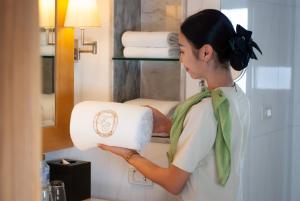 a woman holding a roll of toilet paper in a bathroom at lebua at State Tower in Bangkok