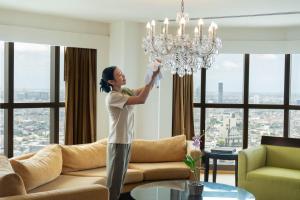 a woman standing in a living room holding up a chandelier at lebua at State Tower in Bangkok