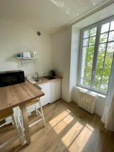 a kitchen with a wooden table and a large window at STUDIO parfaitement agencé in Lamballe