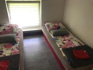 two beds in a room with a window at Tanie Pokoje Kajetany in Kajetany
