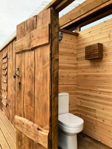 a wooden bathroom with a toilet in a wooden wall at Walltree House Glamping - Bell Tent in Brackley