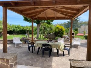 a patio with a table and chairs under a wooden pergola at villamorus in Santa Maria la Palma