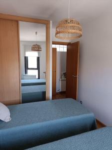 ein Schlafzimmer mit einem blauen Bett und einem Spiegel in der Unterkunft Apartamento Sweet Carolinas in Vilagarcia de Arousa