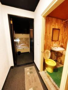 uma casa de banho com um WC amarelo e um lavatório. em Doobaki Hostel em Gyeongju