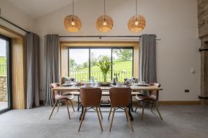 a dining room with a table and chairs and a large window at Canny Grouse Barn in Kirkby Stephen