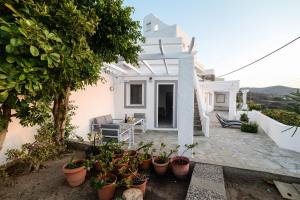 a white house with potted plants on a patio at Gialiskari Studios in Gialiskari