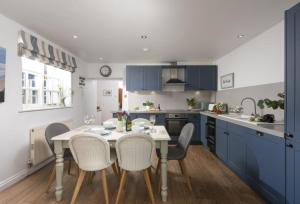 a kitchen with blue cabinets and a table and chairs at Cob Cottage in St. Agnes