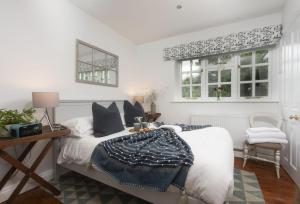 a bedroom with a bed and a chair and windows at Cob Cottage in St. Agnes