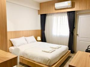 a bedroom with a white bed with a window at PG Ryoichi Hotel in Chiang Rai