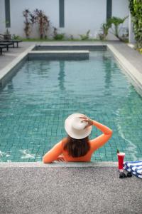 a woman in a hat sitting next to a swimming pool at Hotel Blambangan in Banyuwangi