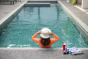 a woman in a hat sitting next to a swimming pool at Hotel Blambangan in Banyuwangi